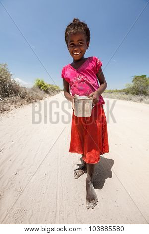 MORONDAVA, MADAGASCAR - DECEMBER 08 Portrait of unidentified smiling girl with can, December 08, 2013, Morondava region, Madagascar. Children in Madagascar are friendly and often barefoot.