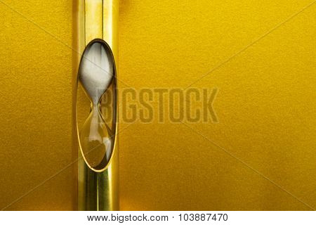 Golden time, gold hour glass in front of gold wall.
