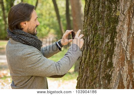 Handsome middle-aged man making photos in the park