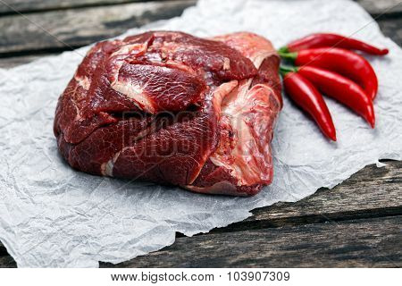 Raw Ox Cheek On Crumpled Paper,  Decorated With Vegetables. On Old  Wooden Table