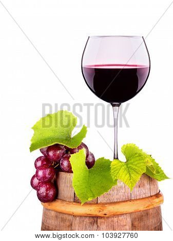 Glass of red wine with grape on a wooden barrel
