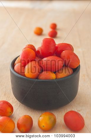 Tomoto Fruit In A Black Bowl On Wooden Backgroud