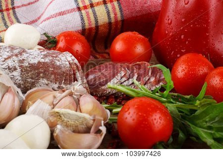 Salami With Cherry Tomatoes, Ruccola And Garlic On A Cutting Board