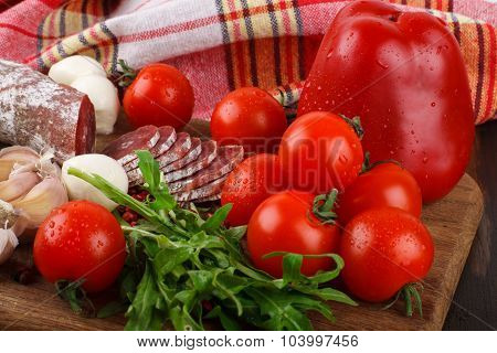 Salami With Cherry Tomatoes, Pepper, Garlic And Rukola On A Cutting Board