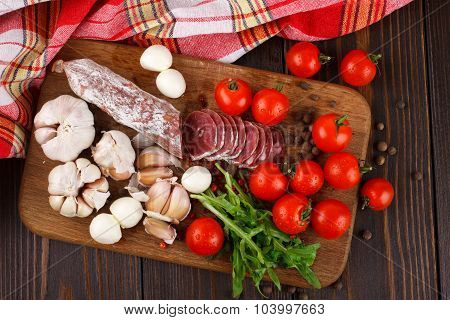 Salami Cherry Tomatoes, Ruccola And Garlic On A Cutting Board