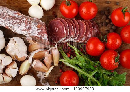 Salami With Cherry Tomatoes, Ruccola And Garlic On A Cutting Board
