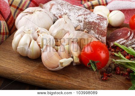 Garlic And Salami With Cherry Tomatoes And Spices On A Cutting Board
