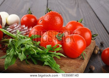 Cherry Tomatoes, Rucola, Salami On A Cutting Board