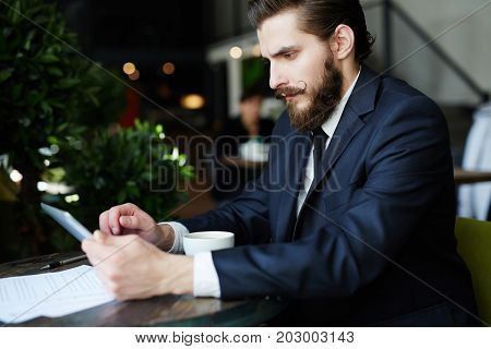 Young economist or trader with tablet searching for financial statistics