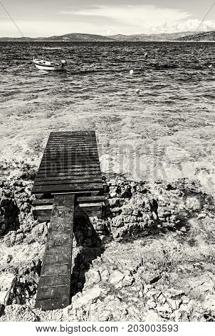 Beautiful Mediterranean sea Solta Croatia. Summer vacation. Springboard and little boat. Black and white photo.