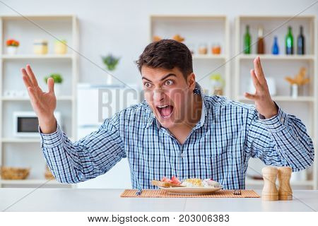 Young husband eating tasteless food at home for lunch