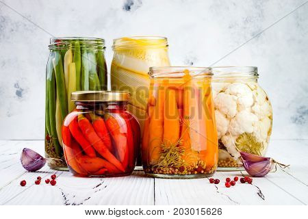 Marinated pickles variety preserving jars. Homemade green beans squash cauliflower carrots red chili peppers pickles. Fermented food.