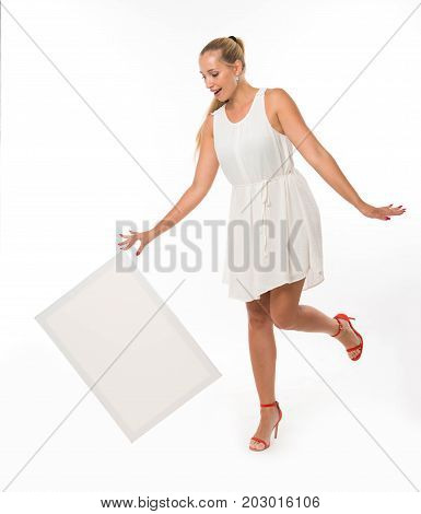 Young jocular woman portrait of a confident businesswoman showing presentation, pointing placard gray background. Ideal for banners, registration forms, presentation, landings, presenting concept.