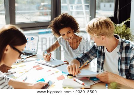 Students life. Positive young students sitting at the table and preparing for exam while studying together