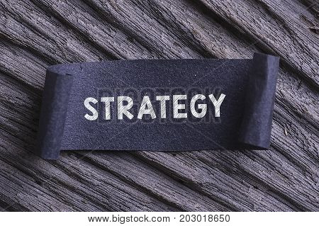 Strategy Word Written On Black Papper With Wooden Background. Rustic And Grany Effect.