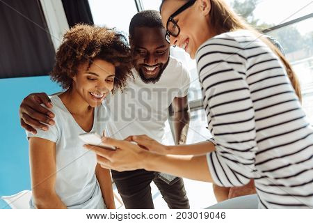 Just look. Cheerful young international students using smart phone and smiling while resting after university