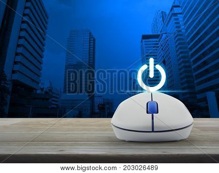 Power button with wireless computer mouse on wooden table over modern office city tower Start up business concept