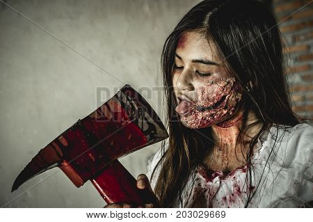 Asian girl dress killer to Halloween festival She holds a giant axe soaked with blood with scary eyes ready to kill people.