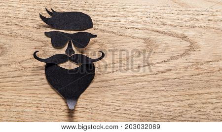 Hipster's definicial facial look cut from paper on the wooden background.