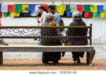 KATHMANDU NEPAL - 9/23/2015: Two elderly women sit on a bench at the Boudhanath Stupa in Kathmandu Nepal.