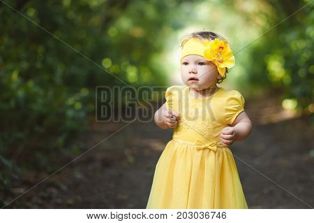 Little girl in a yellow dress alone in the forest.
