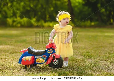 Little girl in a yellow dress near a motorcycle.