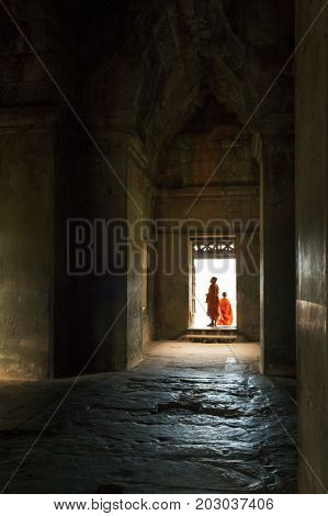 SIEM REAP CAMBODIA - 6/26/2015: Two monks stand in the doorway at the Angkor Wat temple.