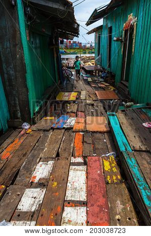 SIHANOUKVILLE CAMBODIA - 7/20/2015: A young boy walks down the colorful path in rural fishing village.