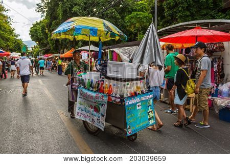 CHIANG MAI THAILAND - 6/13/2015: A drink vendor pushes his cart through the Sunday walking street market.