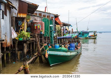 SIHANOUKVILLE CAMBODIA - 7/20/2015: A local resident sweeps her home built on stilts in a fishing village.