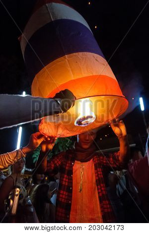 CHIANG MAI THAILAND - 12/30/2015: A male tourist releases a floating lantern at a Buddhist temple on New Year's Eve in Chiang Mai Thailand.