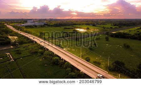Aerial Photo Countryside Car Running on Road Bridge Over Railway Bypass route the City and Golden Hour Sky Beautiful Landscape Drone View