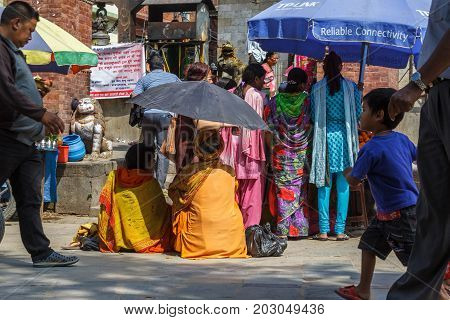 KATHMANDU NEPAL - 9/26/2015: A Sadhu uses an umbrella to block the heat during the Indra Jatra festival at Durbar Square in Kathmandu Nepal.