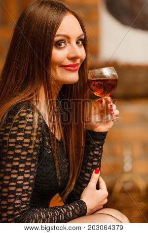 Elegant beauty lady long hair full make up wearing black dress tasting wine in rural cottage interior celler