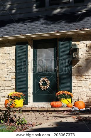 Sun lighted main entrance of the house decorated for autumn holidays season. Vertical composition.