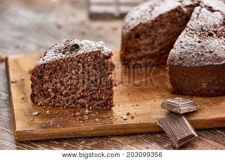 Delicious chocolate cake in white plate on wooden table background, closeup
