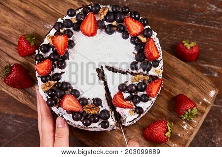 Closeup of Making Sponge Cake with Strawberry. Hand putting icing on freshly baked cake