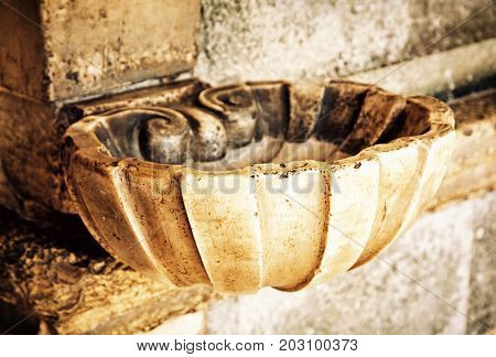 Holy water font. Religious symbol. Yellow photo filter.