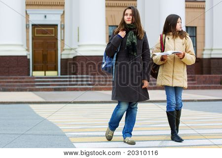 Dos jóvenes estudiantes en el cruce de peatones.