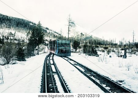 Funicular railway at High Tatras mountains in Slovak republic. Rail cable car leads from Stary Smokovec to ski and tourist resort Hrebienok. Blue photo filter.