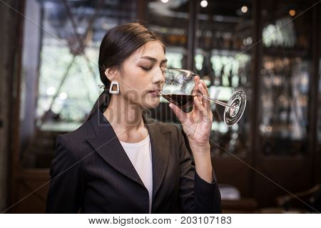 Young Asian Sommelier Woman Tasting Red Wine With Relax Emotion. The Woman Is Holding  Wineglass And