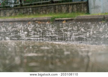 heavy rain drops falling on city asphalt during downpour in autumn