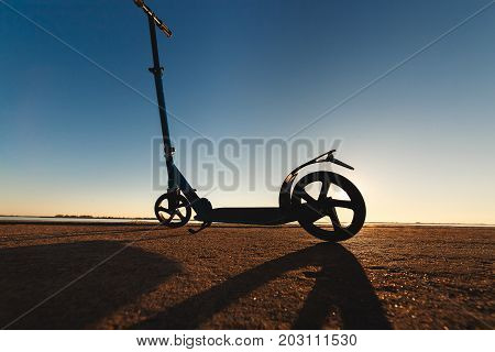 Kick scooter on asphalt running track , under sunlight at sunny summer day. Wide angle image.