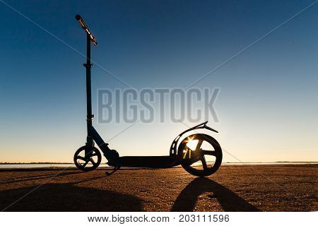 Kick scooter on asphalt running track , under sunlight at sunny summer day. Wide angle image.