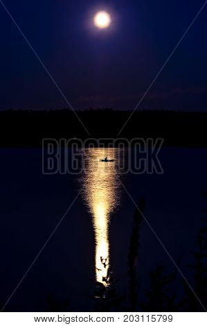 little fishing boot on the river at night lit by the full moon.