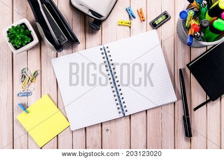 Top view workspace mockup on wooden background with blank notebook with copy space, pen, tacker, punch, clips and accessories. Overhead view. Flat lay, top view