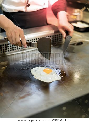 Hand Of Chef Cooking Egg On Hot Pan In Front Of Customers.