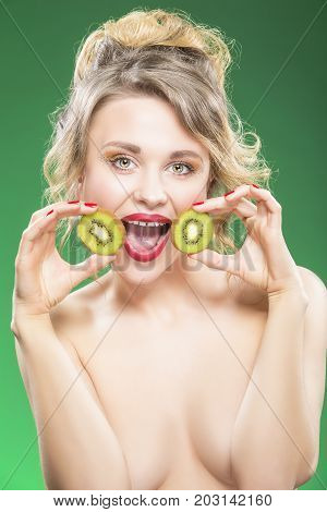 Funny Kiwi Fruit Series. Sensual Funny Nude Caucasian Model Making Faces while Posing With Juicy Kiwi Fruit in Front of Face. Against Green.