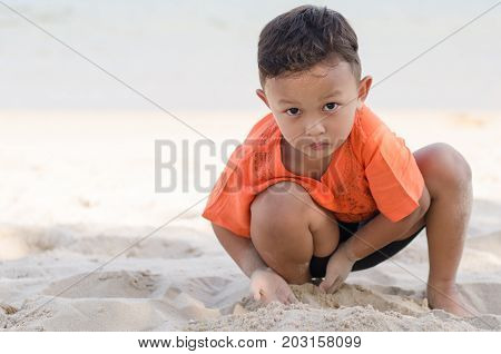 Asian Happy little boy 4-5 year on vacation having fun playing sand on beach