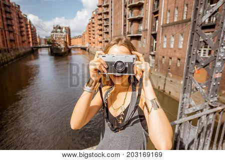Young woman tourist photographing beautiful view on the Speicherstadt, historic warehouse district in Hamburg, Germany